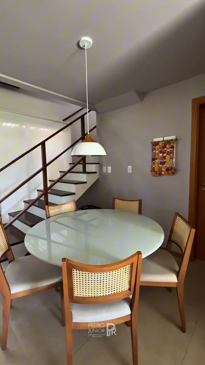 Sala de jantar integrada com mesa redonda e escada do Apartamento Duplex