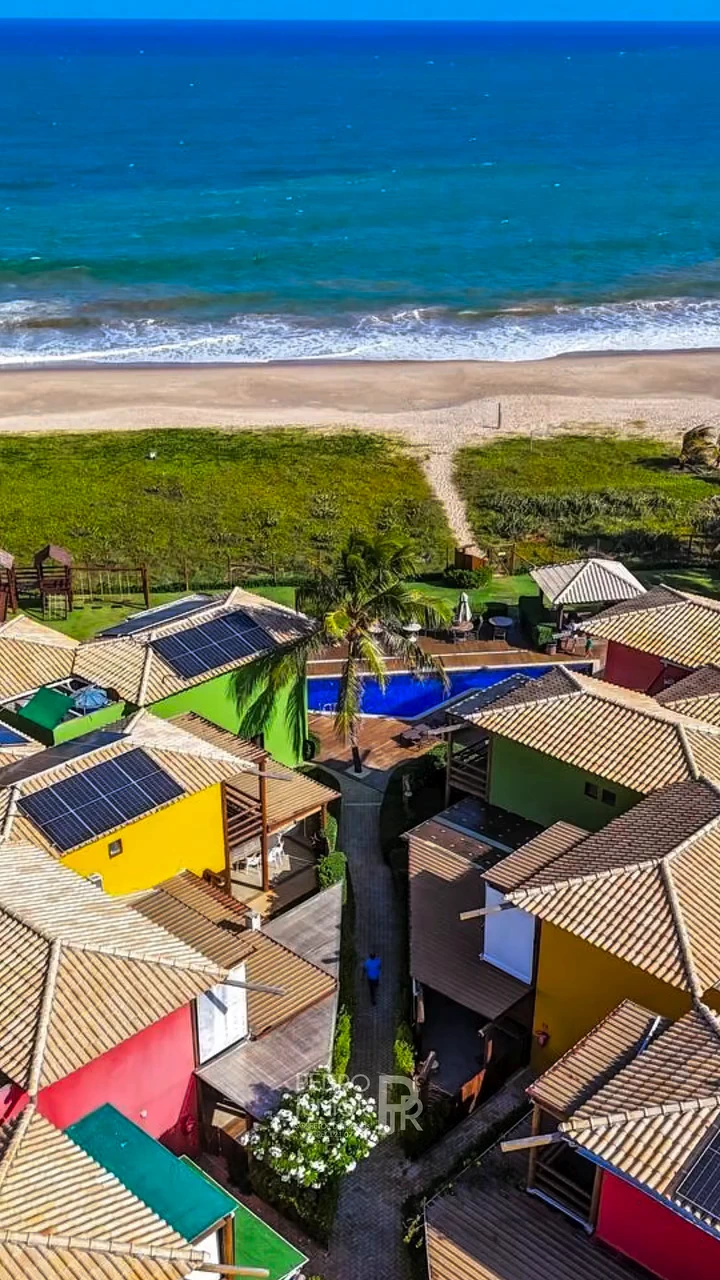 Vista panorâmica aérea do condomínio pé na areia com casas duplex, piscina e acesso direto à praia