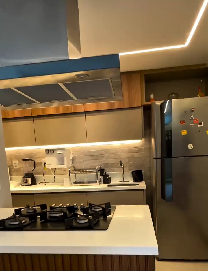 Cozinha americana planejada com bancada em ilha, cooktop, coifa inox e armários sob medida