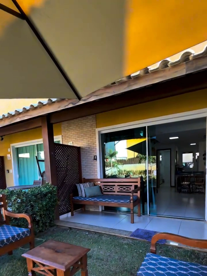 Varanda térrea privativa com jardim, poltronas em madeira e portas integradas à sala