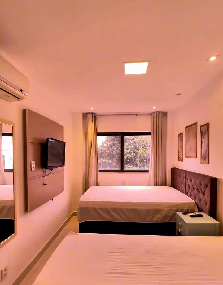 Suíte decorada com duas camas, ar-condicionado split, armário planejado e espelho decorativo